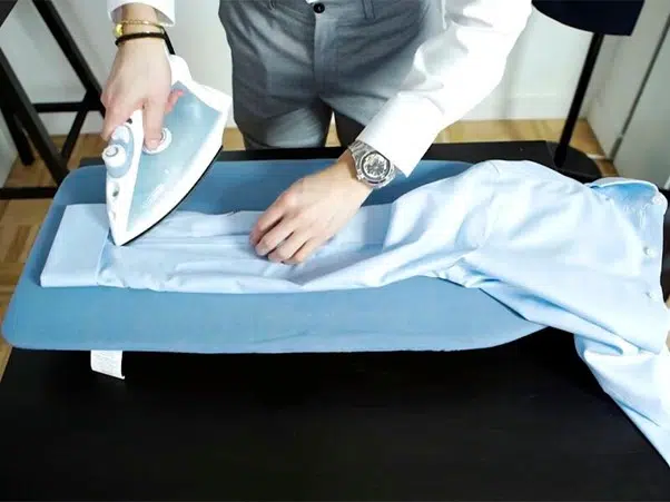 Un homme repasse sa chemise