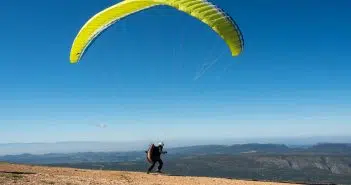 person in black shirt and pants with yellow parachute in the sky