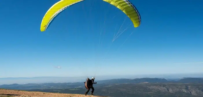 person in black shirt and pants with yellow parachute in the sky