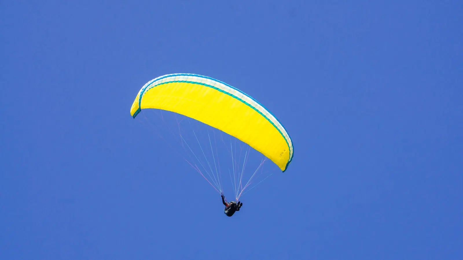 person in yellow parachute under blue sky during daytime