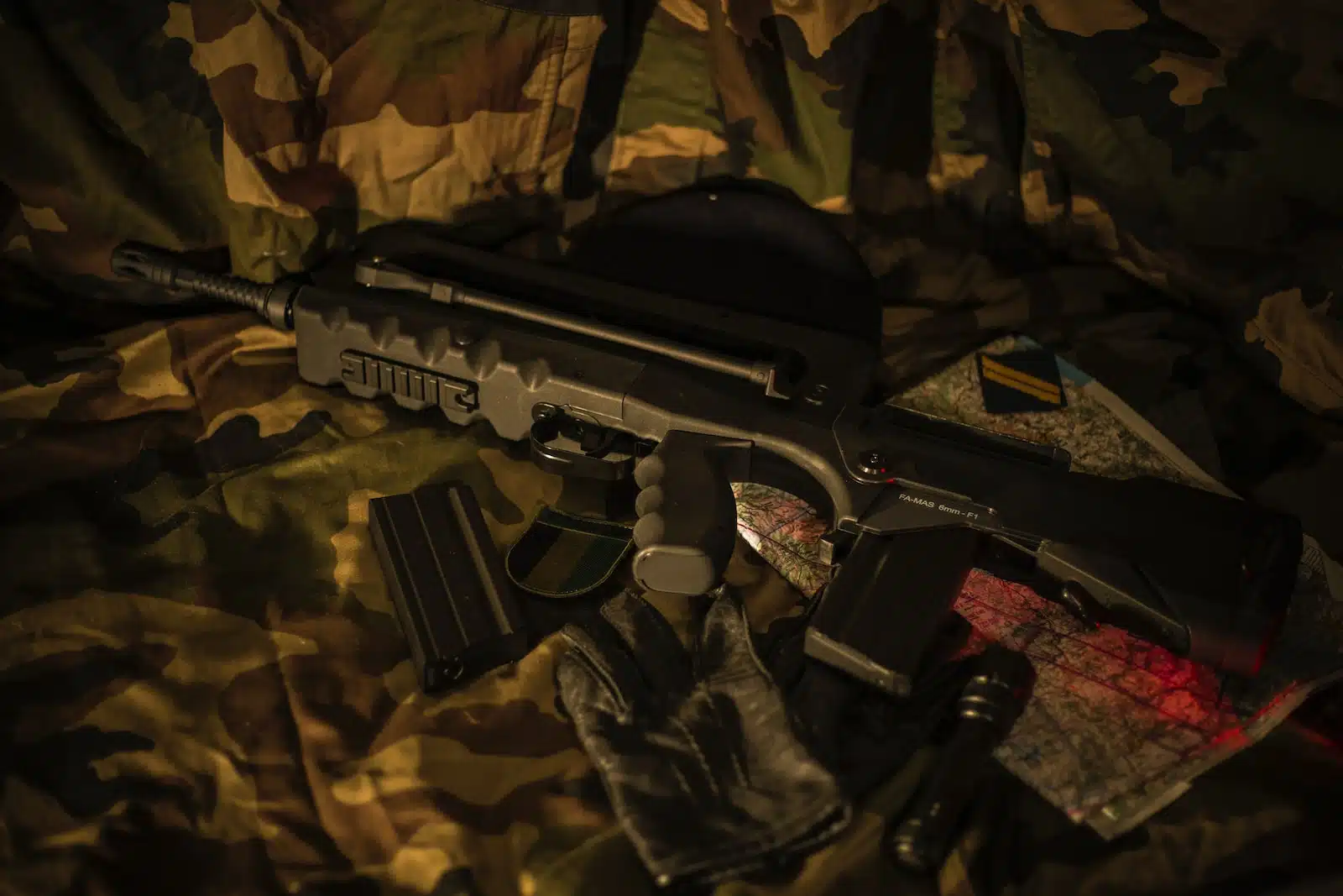 black FAMAS lying on brown camouflage textile