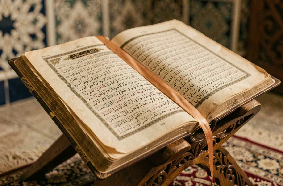 Coran ancien ouvert sur un lutrin en bois sculpté dans une mosquée, révélant les versets arabes des sourates