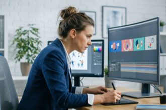Professionnelle en blazer marine révisant des storyboards de motion design sur deux écrans dans un bureau moderne
